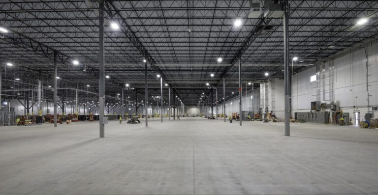 Open warehouse floor with LED high-bay lighting during the electrical fit-out at Amazon SNJ5, Jersey City NJ