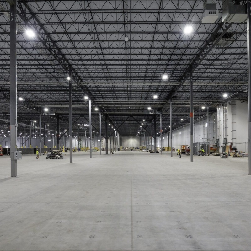 Open warehouse floor with LED high-bay lighting during the electrical fit-out at Amazon SNJ5, Jersey City NJ